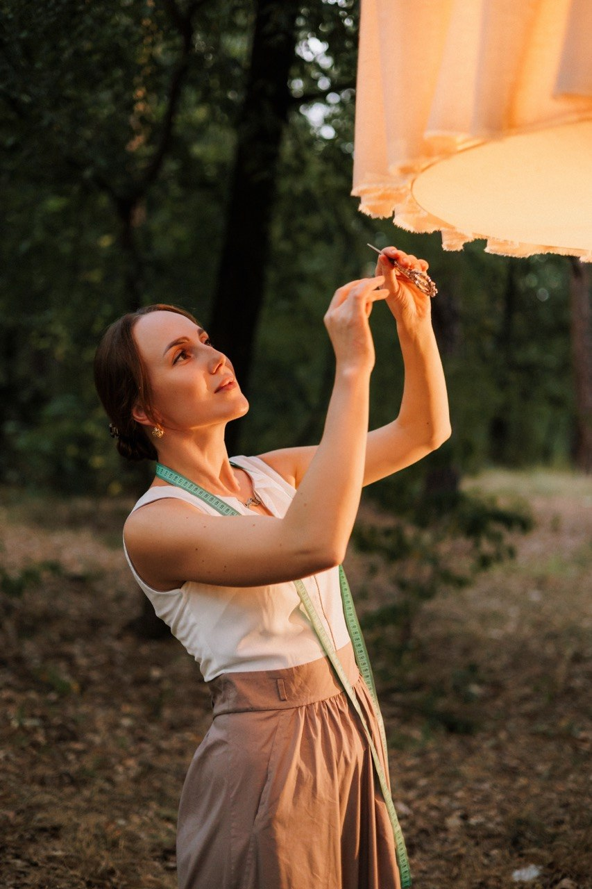 Olga using small tools to refine a glowing handmade pendant light
