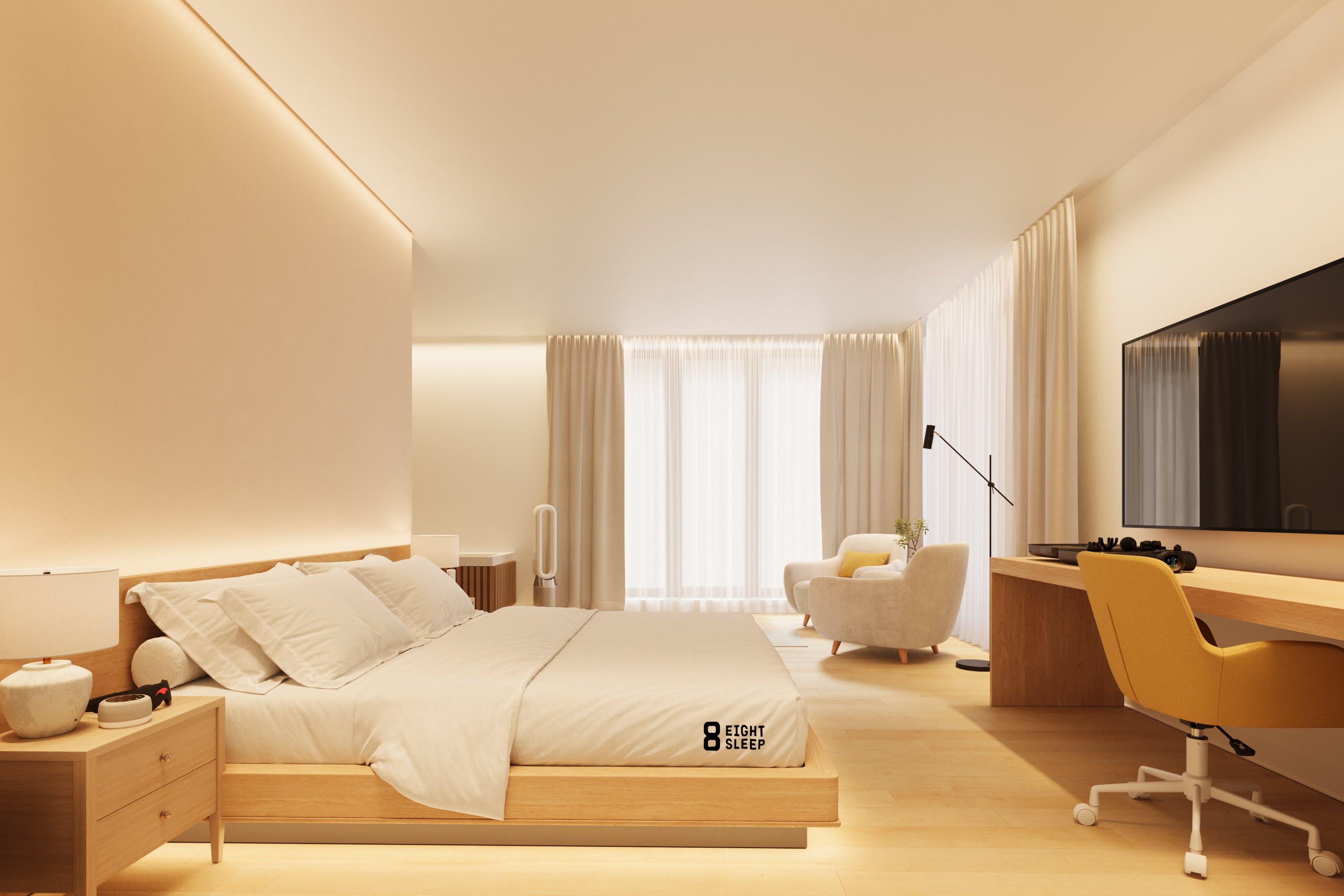 A warm guest room with a low bed, integrated work desk, lounge chair and soft curtains